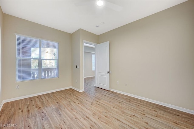 empty room with baseboards, a ceiling fan, and light wood-style floors