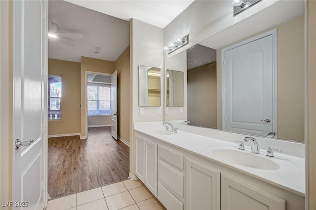 full bathroom with tile patterned flooring, a sink, baseboards, and double vanity