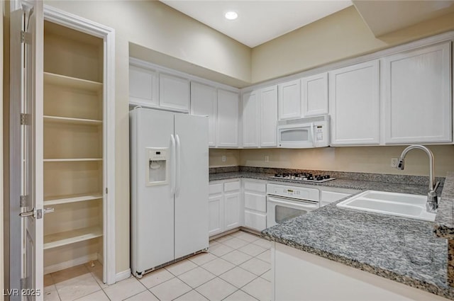 kitchen featuring light tile patterned flooring, recessed lighting, white appliances, a sink, and white cabinetry