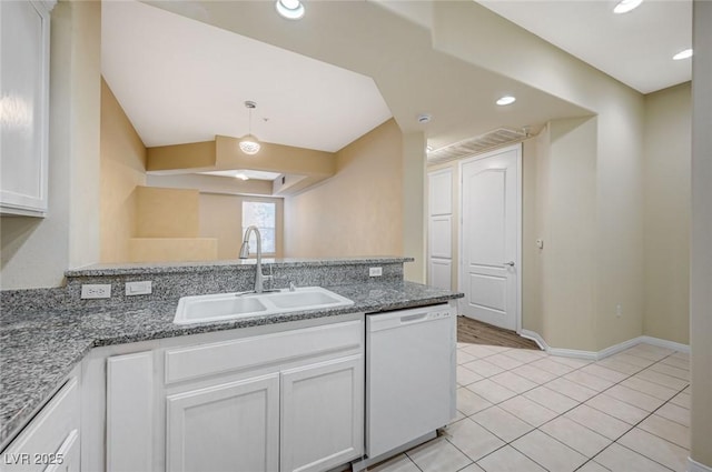 kitchen with white cabinetry, white dishwasher, a sink, dark stone counters, and baseboards