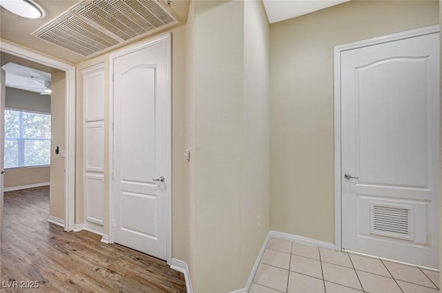 hallway featuring light tile patterned floors, baseboards, and visible vents