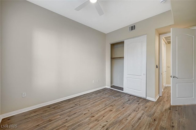 unfurnished bedroom featuring a closet, visible vents, a ceiling fan, wood finished floors, and baseboards