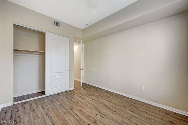 unfurnished bedroom with light wood-style flooring, a closet, visible vents, and baseboards