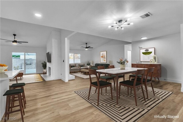 dining space with a wealth of natural light, visible vents, a fireplace, and light wood finished floors