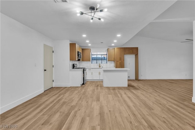 kitchen with open floor plan, appliances with stainless steel finishes, light countertops, and light wood-type flooring