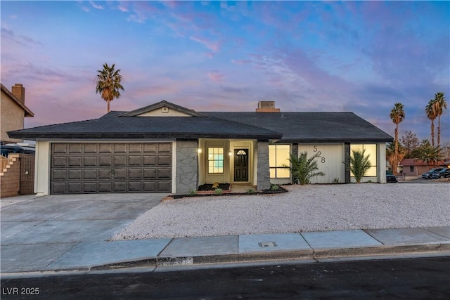 ranch-style house featuring concrete driveway, stone siding, a chimney, and an attached garage