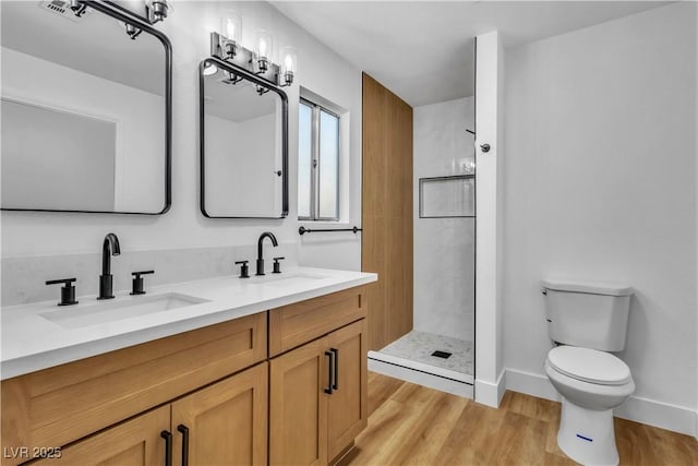 full bath with tiled shower, toilet, wood finished floors, and a sink