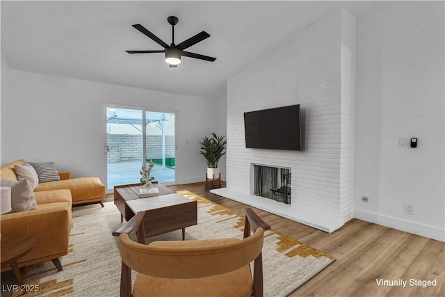 living room featuring ceiling fan, baseboards, lofted ceiling, a fireplace, and wood finished floors