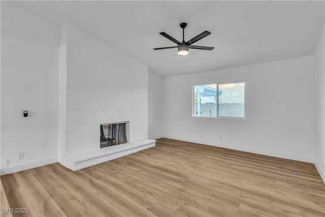 unfurnished living room featuring baseboards, ceiling fan, light wood-type flooring, vaulted ceiling, and a fireplace