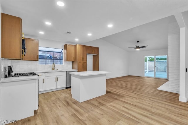 kitchen with a sink, tasteful backsplash, stainless steel appliances, light wood-style floors, and light countertops