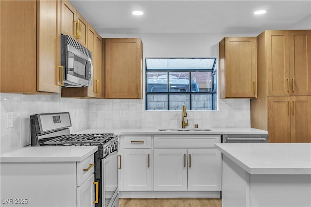 kitchen with recessed lighting, a sink, decorative backsplash, light countertops, and stainless steel appliances