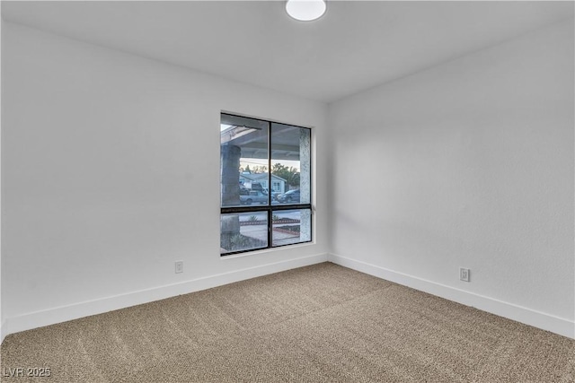 spare room with baseboards and carpet floors