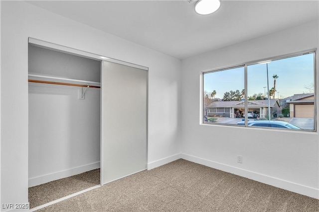 unfurnished bedroom with a closet, baseboards, and carpet