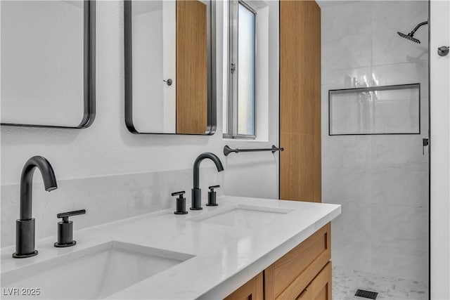 full bathroom with a sink, tiled shower, and double vanity