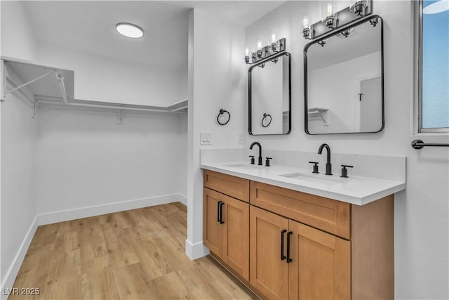 full bathroom featuring double vanity, a spacious closet, wood finished floors, and a sink