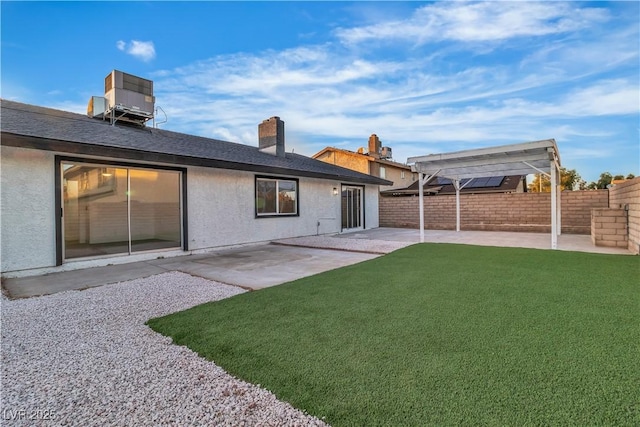 rear view of property with a fenced backyard, central AC unit, a yard, and a patio