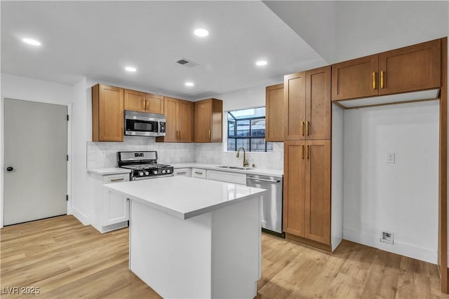 kitchen featuring a sink, decorative backsplash, light countertops, appliances with stainless steel finishes, and light wood-type flooring