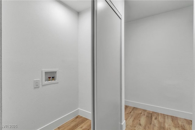 clothes washing area with baseboards, washer hookup, laundry area, and light wood finished floors