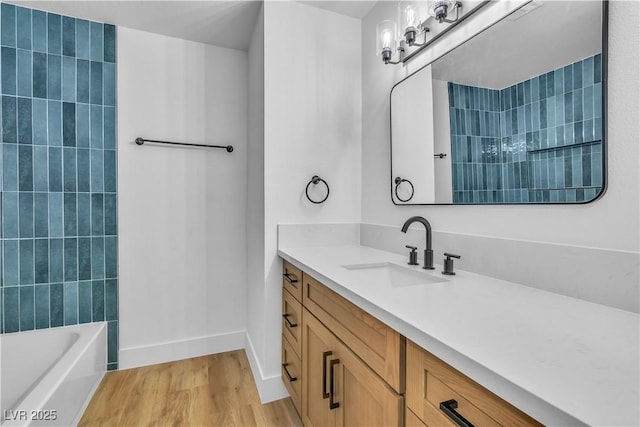 bathroom featuring baseboards,  shower combination, wood finished floors, and vanity