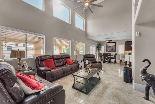living room with light tile patterned floors, baseboards, and ceiling fan