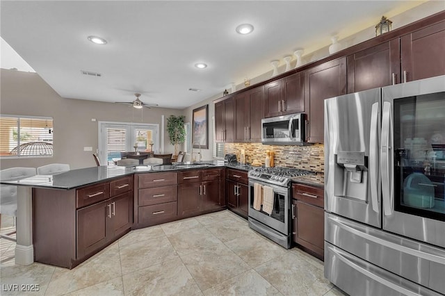 kitchen with dark countertops, visible vents, appliances with stainless steel finishes, a peninsula, and a ceiling fan
