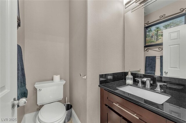 bathroom featuring toilet, vanity, and baseboards
