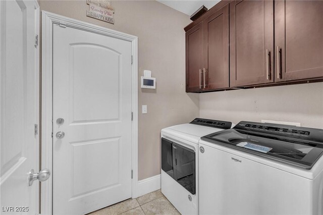 laundry room featuring baseboards, cabinet space, washing machine and dryer, and light tile patterned flooring
