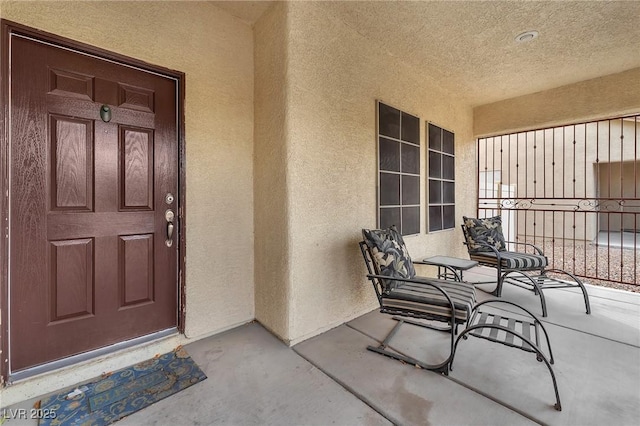 view of exterior entry with stucco siding and covered porch