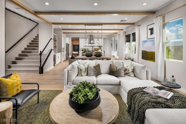 living area featuring beam ceiling, recessed lighting, visible vents, light wood-style floors, and stairs