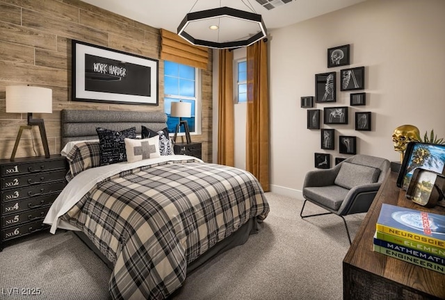 bedroom with an accent wall, carpet floors, wood walls, visible vents, and baseboards