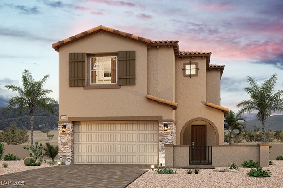 mediterranean / spanish home with a fenced front yard, decorative driveway, stucco siding, a garage, and stone siding