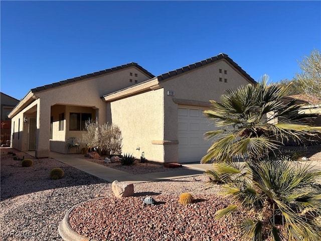 view of side of property featuring an attached garage, a tile roof, and stucco siding