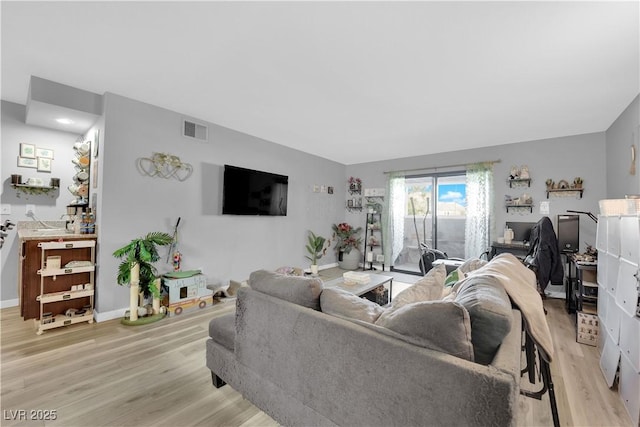 living area featuring baseboards, visible vents, and light wood-style floors