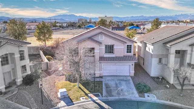 view of front of home with concrete driveway, a tiled roof, an attached garage, a mountain view, and stucco siding