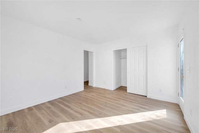 unfurnished bedroom featuring light wood finished floors, baseboards, and a closet