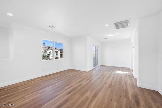 unfurnished room featuring wood finished floors, visible vents, and baseboards