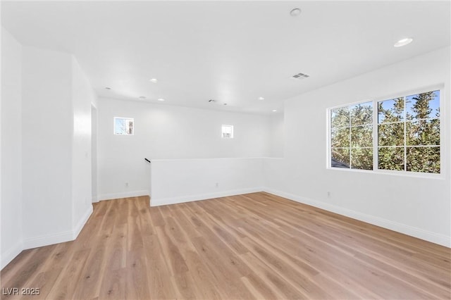 unfurnished room with light wood-type flooring, baseboards, visible vents, and recessed lighting