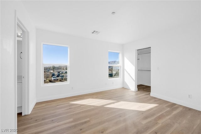 unfurnished bedroom with visible vents, ensuite bathroom, light wood-style flooring, and baseboards