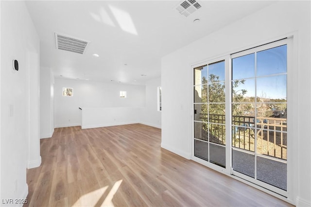 empty room with baseboards, visible vents, and light wood-style floors