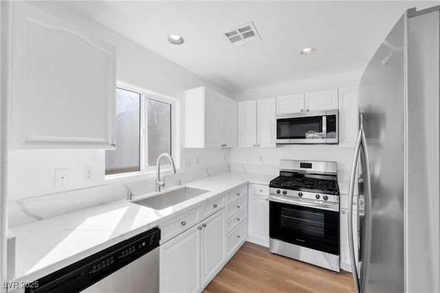 kitchen featuring light stone countertops, visible vents, appliances with stainless steel finishes, and a sink