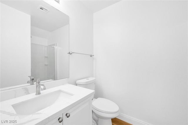 full bathroom featuring toilet, vanity, visible vents, baseboards, and walk in shower