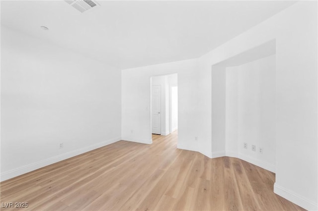 empty room featuring light wood-style floors, visible vents, and baseboards