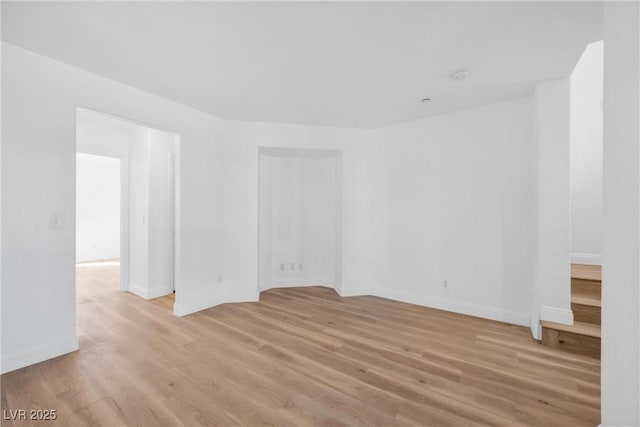 empty room featuring light wood-type flooring and baseboards