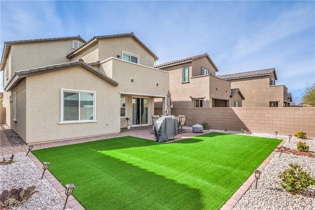 rear view of property featuring a lawn, a patio area, a fenced backyard, and stucco siding