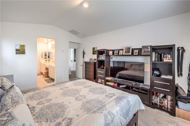 bedroom with lofted ceiling, ensuite bathroom, light colored carpet, visible vents, and baseboards