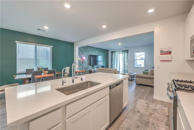 kitchen featuring light countertops, appliances with stainless steel finishes, open floor plan, white cabinets, and a sink