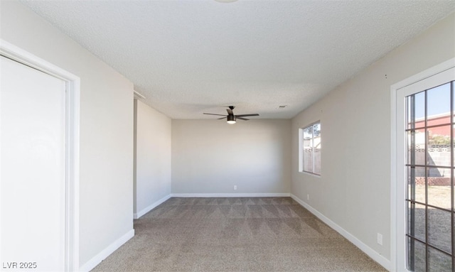 empty room featuring a textured ceiling, plenty of natural light, baseboards, and light colored carpet