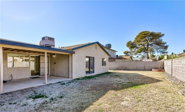 rear view of house featuring a patio area, a fenced backyard, central AC, and stucco siding