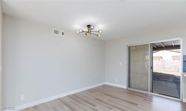 unfurnished room with baseboards, light wood-style floors, visible vents, and a notable chandelier