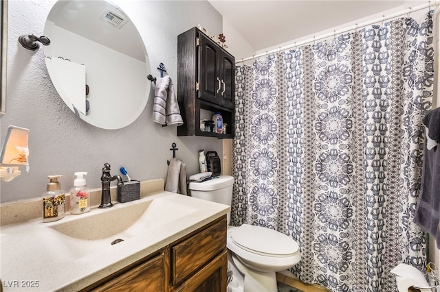 bathroom with visible vents, a textured wall, vanity, and toilet